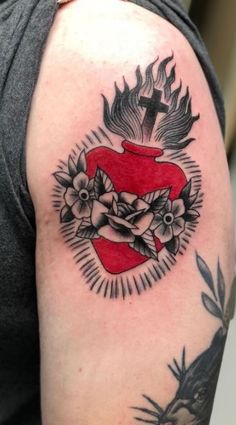 a woman with a tattoo on her arm has a cross and flowers in the shape of a heart