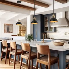 a large kitchen with blue cabinets and white counter tops, along with bar stools