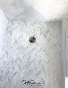 a bathroom shower with white marble and gold grouting on the wall next to it