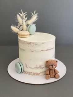 a white cake with frosting and a teddy bear on the side sitting next to it