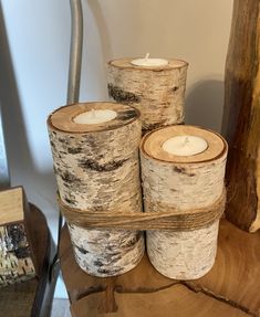 four birch logs are stacked next to each other on a wooden table with a candle in the middle