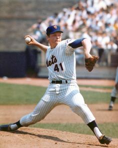 a baseball player pitching a ball on top of a field in front of a crowd