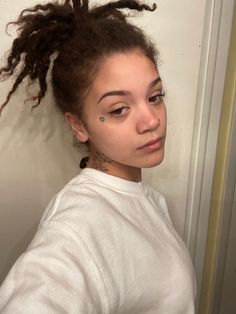 a young woman with dreadlocks standing in front of a door and looking at the camera