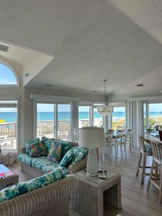 a living room filled with furniture next to a dining table and ocean front view window