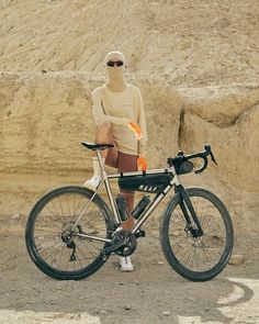 a man in a hoodie sitting on a bike next to a pile of dirt