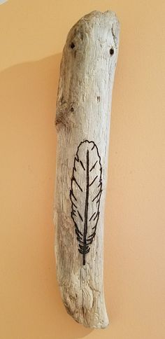 a piece of wood that has been carved into the shape of a tree branch with a drawing of a feather on it