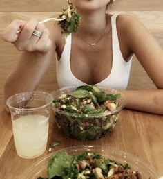 a woman sitting at a table eating salad