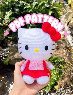 a hello kitty crochet doll is shown in front of some plants