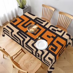 a table with an orange and black tablecloth on it, surrounded by wooden chairs