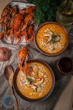 two bowls of soup with lobsters and garlic on the side, next to some bread