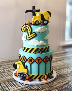 a three tiered cake with construction vehicles on it's sides and blue icing