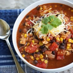 a white bowl filled with chili, beans and cheese on top of a blue towel