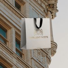 a white bag hanging from the side of a building with an excellent faces logo on it