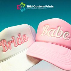 two hats that say bride and babe on the front, one pink and one white