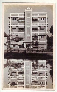 an old black and white photo of a building reflecting in the water