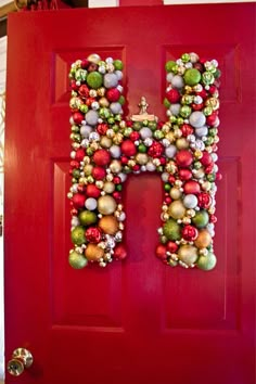 the letter h is made out of christmas balls and ornaments on a red front door