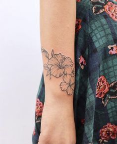 a woman's arm with a flower tattoo on the left side of her arm