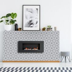 a modern fireplace in a living room with potted plants on the mantle and pictures above it