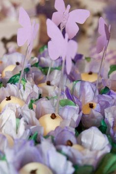 there are many cupcakes with purple butterflies on them in the shape of flowers