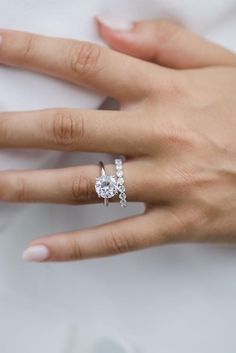 a woman's hand with a diamond ring on her finger and the other hand holding an engagement ring