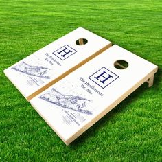 two white cornhole game boards sitting on top of green grass