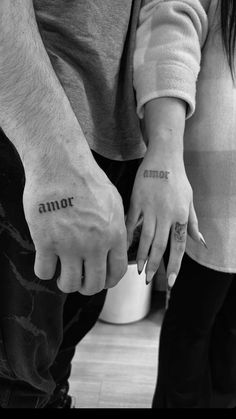 two people holding hands with tattoos on their fingers and one has the word minor written on it