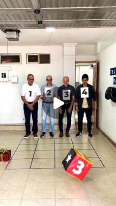 four men standing in a room with numbers on their shirts