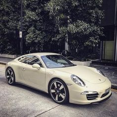 a white sports car parked on the side of the road in front of some trees