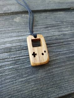 a wooden pendant with a cross on it sitting on a wooden table next to a string