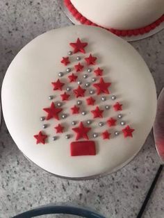 a white cake decorated with red and silver stars on top of a table next to a knife