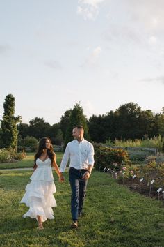 a man and woman holding hands walking through the grass