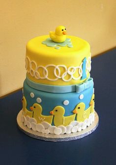 a cake decorated with rubber ducks on a blue tablecloth and white trimmings