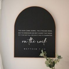 a black and white sign hanging on the wall next to a vase filled with flowers