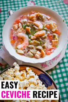 a bowl of shrimp and vegetable soup next to a plate of popcorn on a checkered tablecloth