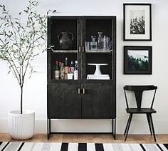 a black cabinet sitting in the corner of a living room next to a white rug