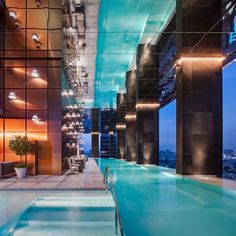 an indoor swimming pool in the middle of a building with glass walls and floor to ceiling windows