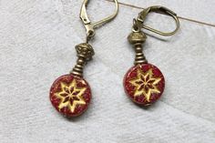 "Very feminine and pretty dangle earrings made with dark red Czech glass beads featuring a star in a gold wash. Adorned with antique brass findings which give to these earrings an antique rustic look. They hang from brass lever backs ( lead and nickel free ). Leverbacks keep your earrings on securely by creating a closed loop.  They're light and small in length. They combine simplicity and charm to fit any casual or formal event.  Color : translucent red opal coin with a gold wash - rustic, earthy star or flower Czech glass beads Finish : Antiqued Brass findings Length : 1,5 inches including the antiqued brass lever back Ear wires : Antiqued Brass lever back Czech Glass Earrings : https://www.etsy.com/shop/NtikArtJewelry?ref=hdr_shop_menu§ion_id=16062218 To visit my shop : https://www.etsy Red Drop Clip-on Earrings As Gift, Handmade Red Czech Glass Beaded Earrings, Red Drop Clip-on Earrings For Gift, Elegant Red Czech Glass Earrings, Nickel-free Red Beaded Round Earrings, Red Beaded Czech Glass Earrings, Adjustable Red Czech Glass Beaded Earrings, Red Clip-on Earrings As Gift, Red Beaded Dangle Earrings