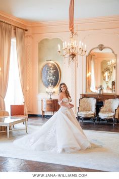 a woman in a white wedding dress posing for a photo by a chandelier