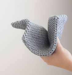 a hand holding a knitted object in the shape of an elephant's tail