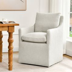 a white chair sitting next to a table with a book on it's side