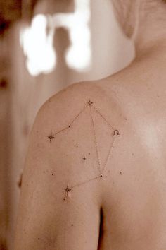 the back of a woman's shoulder with small stars on her left arm and an arrow in the middle