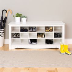 a white shelf with shoes and umbrellas on it