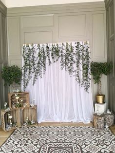 an indoor wedding ceremony with white drapes and greenery draped over the stage curtain