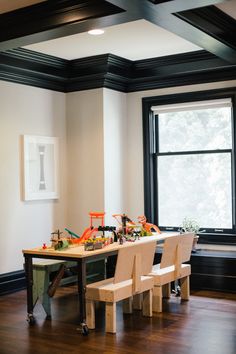 a dining room table with four chairs in front of it and an art work on the wall