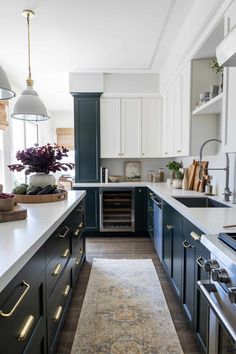 a kitchen with blue cabinets and an area rug on the floor in front of it