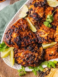 grilled chicken with cilantro and limes on a white plate next to pita bread