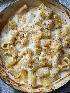 a pan filled with macaroni and cheese on top of a blue table cloth