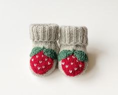 a pair of knitted baby booties with a strawberry on the front and bottom