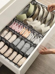 a drawer is open with several pairs of shoes in it and someone's hand reaching for them