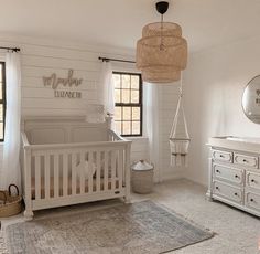 a baby's room with a crib, dresser and mirror